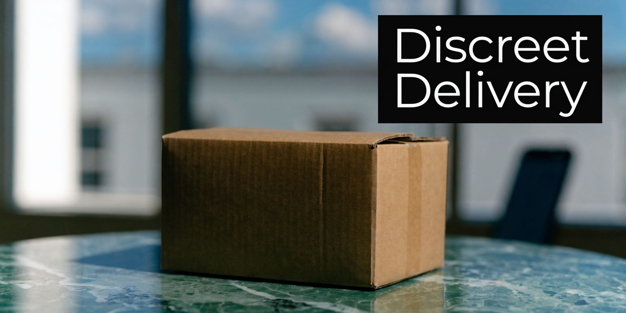 A brown cardboard shipping box sits on a polished green marble table with discreet delivery text overlaid.