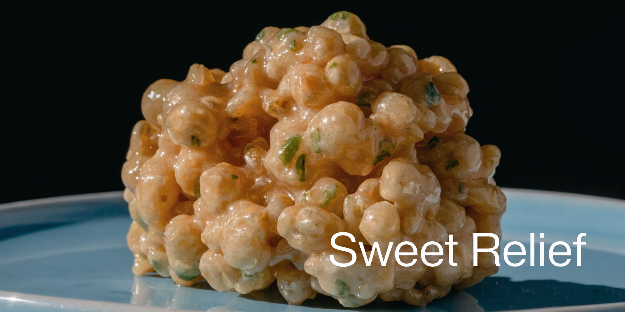 A close-up of a sticky, glazed THC rice crispy treat ball on a blue plate.