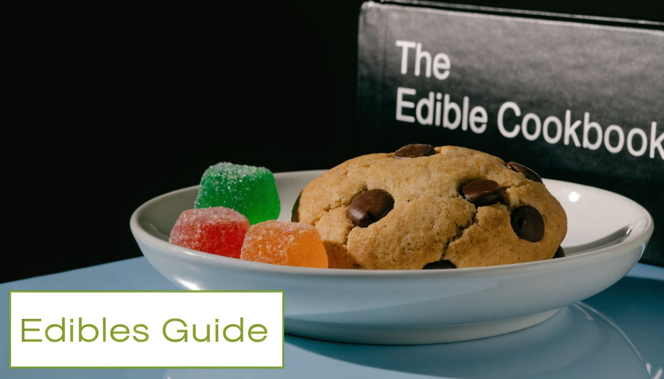 A plate featuring a chocolate chip cookie and colorful gummy candies next to The Edible Cookbook.